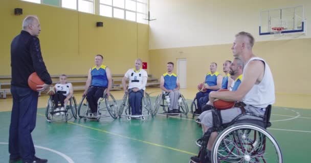 Селектор Я пояснюю нову тактику баскетболістам на інвалідних візках, особам з обмеженими можливостями, які сидять на інвалідних візках, слухаючи селектор — стокове відео