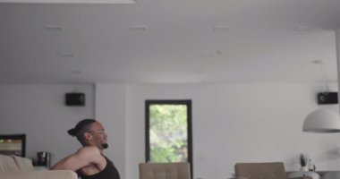 Afro-Amerikan atletik adam dizüstü bilgisayarda online eğitim dersleri izliyor, eğitmenden sonra hareketleri tekrarlıyor, evde bacak egzersizleri yapıyor. Kendini soyutlama. Karantina.