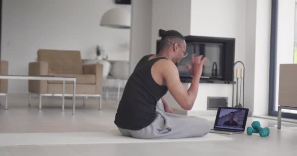 African American γυμναστής γυμναστήριο χρησιμοποιώντας φορητό υπολογιστή για online εκπαίδευση με τον πελάτη κατά τη διάρκεια της πανδημίας coronavirus. — Αρχείο Βίντεο