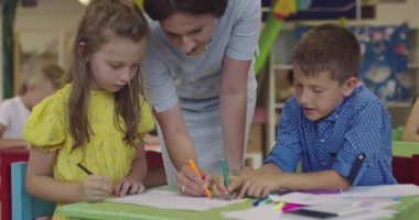 Bir kreşteki resim dersinde yaratıcı çocuklar ya da ilkokul sınıfında bayan öğretmenle resim çizen çocuklar.. 