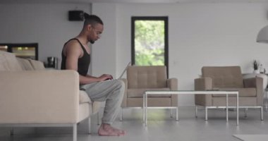 Coronavirus salgını sırasında müşteriyle çevrimiçi eğitim için dizüstü bilgisayar kullanan Afrikalı Amerikalı fitness eğitmeni.