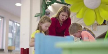 Bir kreşteki resim dersinde yaratıcı çocuklar ya da ilkokul sınıfında bayan öğretmenle resim çizen çocuklar.. 