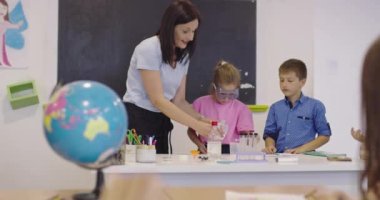 İlköğretim Okulu Bilim Sınıfı: Coşkulu Öğretmen Kimyayı Çeşitli Çocuklar Grubu 'na Açıkladı, Küçük Çocuk Kimyasalları Beakers' a Karıştırdı. Çocuklar Faiziyle Öğrenin