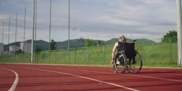 Жінка з обмеженими можливостями їде на інвалідному візку на тренувальному треку — стокове відео