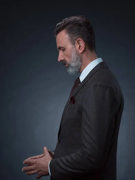 Retrato de un elegante y elegante hombre de negocios con barba y ropa de negocios casual en un estudio fotográfico aislado sobre un fondo oscuro con las manos — Foto de Stock