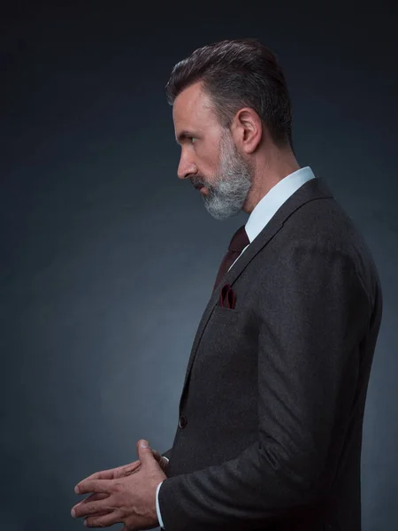 Retrato de un elegante y elegante hombre de negocios con barba y ropa de negocios casual en un estudio fotográfico aislado sobre un fondo oscuro con las manos —  Fotos de Stock