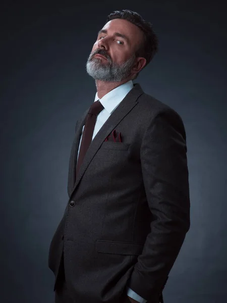 Retrato de un elegante y elegante hombre de negocios con barba y ropa de negocios casual en un estudio fotográfico aislado sobre un fondo oscuro con las manos — Foto de Stock