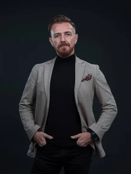 Portrait of a stylish elegant senior businessman with a beard and casual business clothes in photo studio isolated on dark background gesturing with hands — Stock Photo, Image