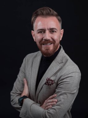 Fotoğraf stüdyosunda sakallı ve sıradan iş kıyafetleri giyen zarif bir kıdemli işadamının portresi. Koyu renk arka planda el kol hareketleriyle izole edilmiş.