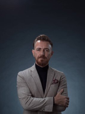 Fotoğraf stüdyosunda sakallı ve sıradan iş kıyafetleri giyen zarif bir kıdemli işadamının portresi. Koyu renk arka planda el kol hareketleriyle izole edilmiş.