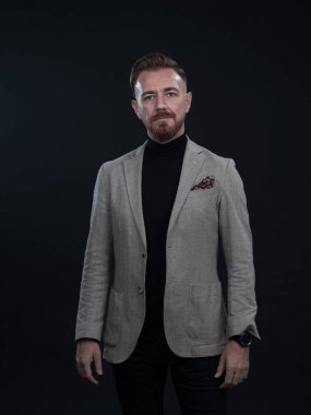 Fotoğraf stüdyosunda sakallı ve sıradan iş kıyafetleri giyen zarif bir kıdemli işadamının portresi. Koyu renk arka planda el kol hareketleriyle izole edilmiş.