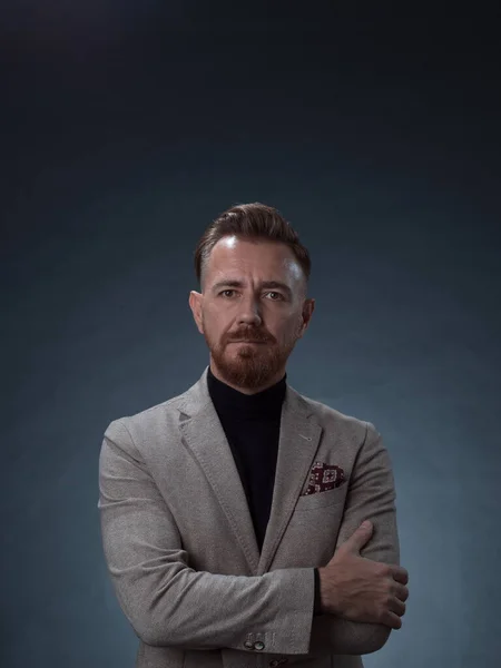 Retrato de un elegante y elegante hombre de negocios con barba y ropa de negocios casual en un estudio fotográfico aislado sobre un fondo oscuro con las manos — Foto de Stock