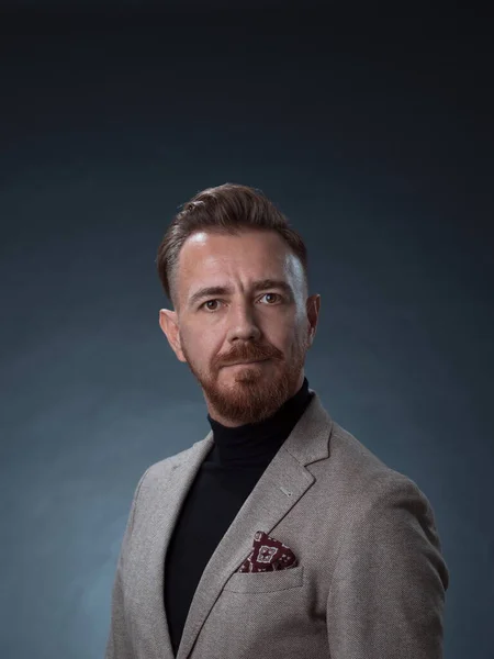 Retrato de un elegante y elegante hombre de negocios con barba y ropa de negocios casual en un estudio fotográfico aislado sobre un fondo oscuro con las manos —  Fotos de Stock