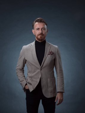 Fotoğraf stüdyosunda sakallı ve sıradan iş kıyafetleri giyen zarif bir kıdemli işadamının portresi. Koyu renk arka planda el kol hareketleriyle izole edilmiş.