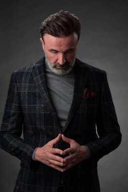 Fotoğraf stüdyosunda sakallı ve sıradan iş kıyafetleri giyen zarif bir kıdemli işadamının portresi. Koyu renk arka planda el kol hareketleriyle izole edilmiş.