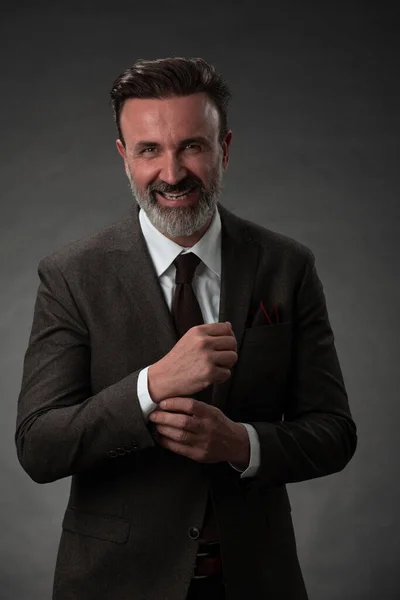 Retrato de um elegante homem de negócios sênior elegante com barba e roupas de negócios casuais em estúdio de fotos ajustando terno — Fotografia de Stock