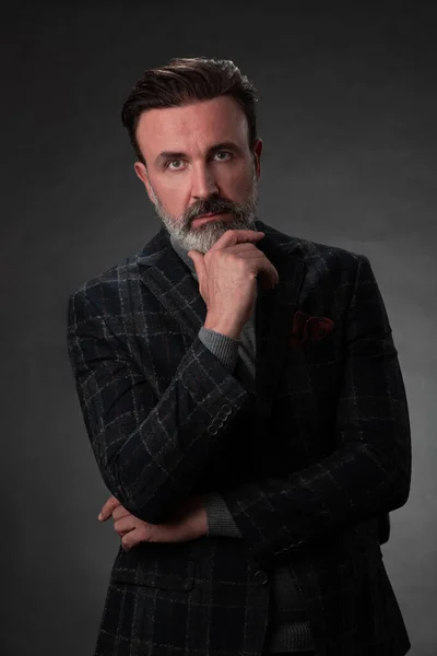 Porträtt av en elegant senior affärsman med skägg och casual business kläder i fotostudio isolerad på mörk bakgrund gester med händerna — Stockfoto