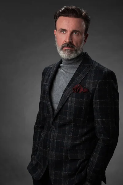 Retrato de un elegante y elegante hombre de negocios con barba y ropa de negocios casual en un estudio fotográfico aislado sobre un fondo oscuro con las manos — Foto de Stock