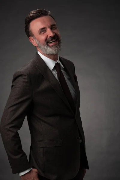 Retrato de un elegante y elegante hombre de negocios con barba y ropa de negocios casual en un estudio fotográfico aislado sobre un fondo oscuro con las manos — Foto de Stock