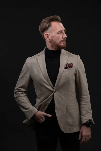 Portrait of a stylish elegant senior businessman with a beard and casual business clothes in photo studio isolated on dark background gesturing with hands — Stock Photo, Image