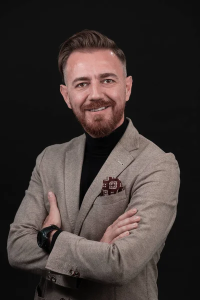 Retrato de un elegante y elegante hombre de negocios con barba y ropa de negocios casual en un estudio fotográfico aislado sobre un fondo oscuro con las manos — Foto de Stock