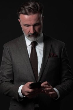 Yetişkin iş adamının son moda takım elbiseli portresi ve modern stüdyoda siyah arka planda şık bir sandalyede oturuyor.