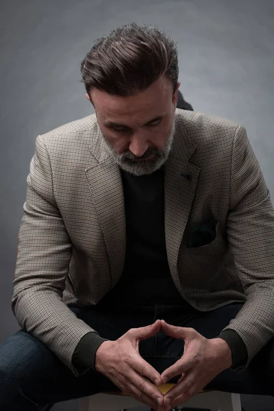 Retrato de un elegante y elegante hombre de negocios con barba y ropa de negocios casual en un estudio fotográfico aislado sobre un fondo oscuro con las manos — Foto de Stock