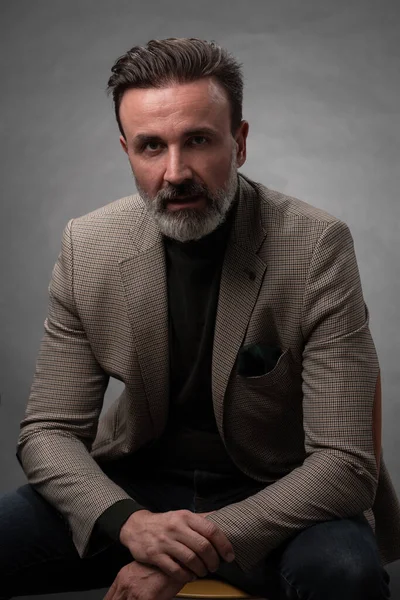 Porträt eines eleganten Geschäftsmannes mit Bart und lässiger Businesskleidung im Fotostudio, isoliert auf dunklem Hintergrund, gestikulierend mit den Händen — Stockfoto