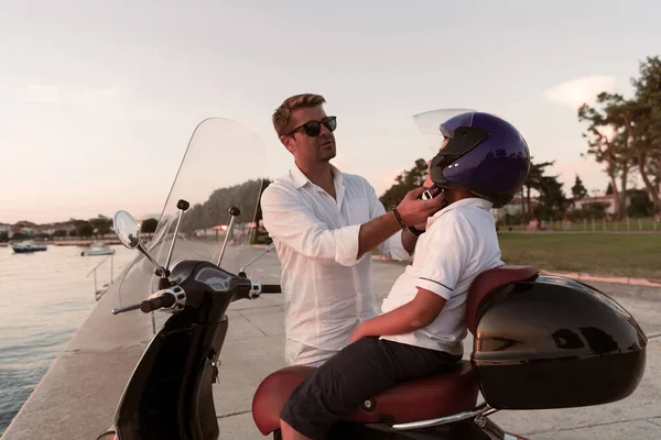 Un padre con su hijo disfruta de unas vacaciones en un scooter junto al mar por la mañana temprano. Enfoque selectivo —  Fotos de Stock