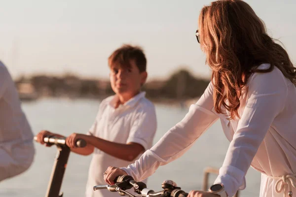 Famiglia felice godendo di una bella mattina al mare insieme, i genitori in sella a una bicicletta e il loro figlio in sella a uno scooter elettrico. Focus selettivo — Foto Stock