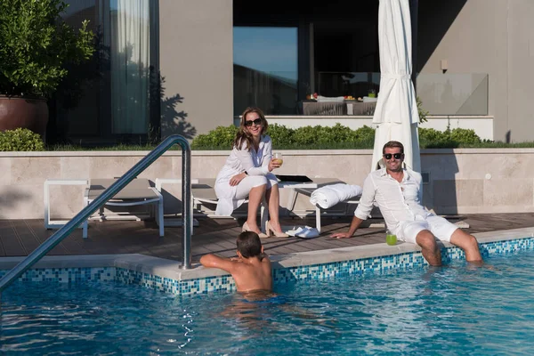 Felice famiglia gode di una vacanza in una casa di lusso con piscina. Coppia di anziani trascorre del tempo con il figlio durante le vacanze. Focus selettivo — Foto Stock