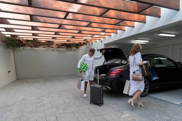 Una foto de una familia moderna que lleva maletas desde un garaje hasta su lujosa casa junto al mar durante unas vacaciones. Concepto de vacaciones. Enfoque selectivo —  Fotos de Stock