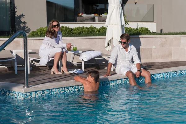 Szczęśliwa rodzina cieszy się wakacjami w luksusowym domu z basenem. Starsza para spędza czas z synem podczas wakacji. Skupienie selektywne — Zdjęcie stockowe