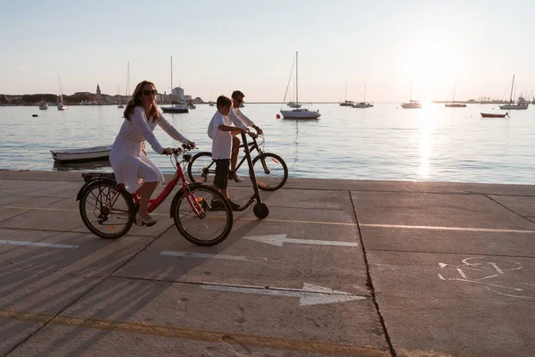 Famiglia felice godendo di una bella mattina al mare insieme, i genitori in sella a una bicicletta e il loro figlio in sella a uno scooter elettrico. Focus selettivo — Foto Stock