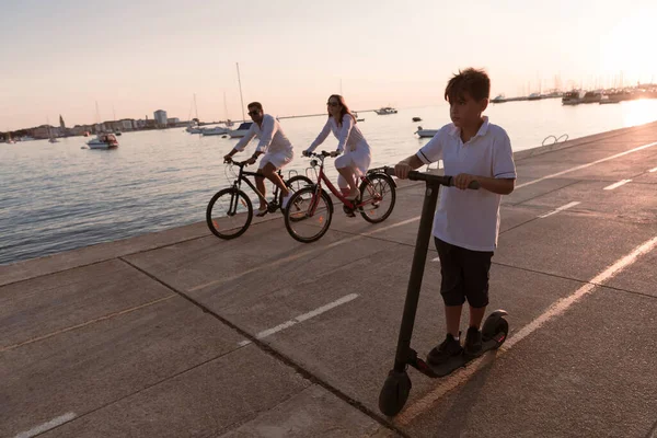 부모들은 자전거를 타고 있고 아들은 전기 스쿠터를 타고 있다. 선택적 초점 — 스톡 사진