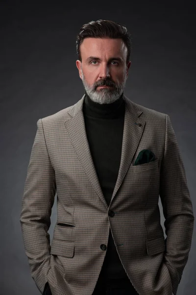 Porträtt av en elegant senior affärsman med skägg och casual business kläder i fotostudio isolerad på mörk bakgrund gester med händerna — Stockfoto