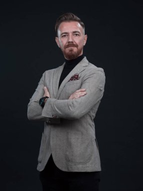 Fotoğraf stüdyosunda sakallı ve sıradan iş kıyafetleri giyen zarif bir kıdemli işadamının portresi. Koyu renk arka planda el kol hareketleriyle izole edilmiş.