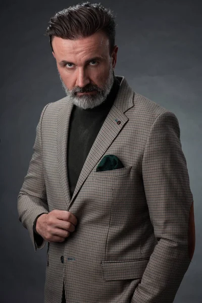 Ritratto di un elegante uomo d'affari anziano elegante con barba e abiti da lavoro casual in studio fotografico isolato su sfondo scuro gesticolando con le mani — Foto Stock