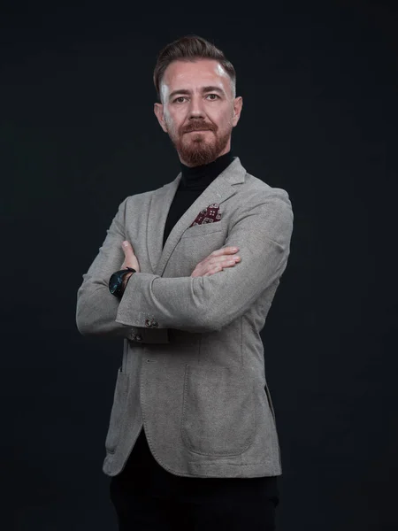 Retrato de un elegante y elegante hombre de negocios con barba y ropa de negocios casual en un estudio fotográfico aislado sobre un fondo oscuro con las manos — Foto de Stock