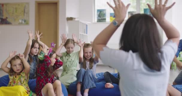 Professeur d'école élémentaire ou primaire lisant une histoire à un groupe d'enfants dans une garderie. — Video