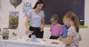 İlköğretim Okulu Bilim Sınıfı: Coşkulu Öğretmen Kimyayı Çeşitli Çocuklar Grubu 'na Açıkladı, Küçük Çocuk Kimyasalları Beakers' a Karıştırdı. Çocuklar Faiziyle Öğrenin