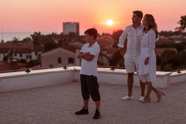 Glückliche Familie genießt und verbringt Zeit zusammen auf dem Dach des Hauses, während sie gemeinsam den Sonnenuntergang auf dem offenen Meer beobachten — Stockfoto