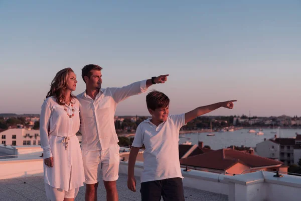 Famille heureuse profite et passe du temps ensemble sur le toit de la maison tout en regardant le coucher de soleil sur la mer ouverte ensemble — Photo