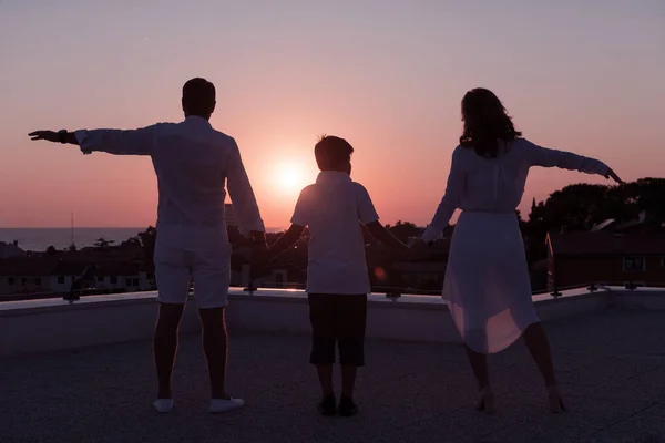 Famiglia felice gode e trascorre del tempo insieme sul tetto della casa mentre si guarda il tramonto sul mare aperto insieme — Foto Stock