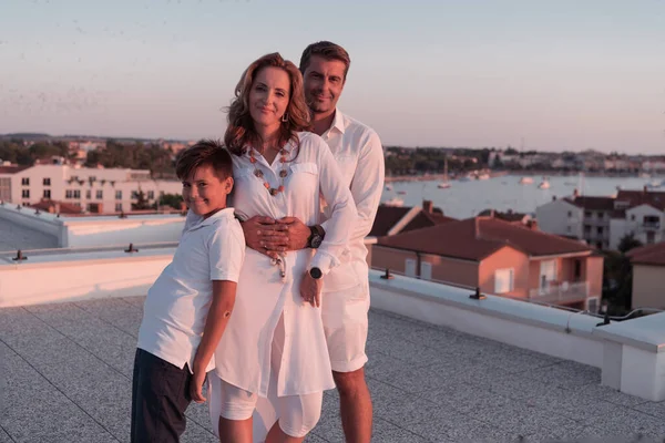 海の夕日を眺めながら家の屋根の上で一緒に楽しい時間を過ごす幸せな家族 — ストック写真