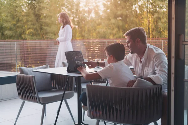 Una feliz pareja de ancianos descansando en el balcón de una casa de lujo, padre e hijo usando una tableta. Enfoque selectivo — Foto de Stock