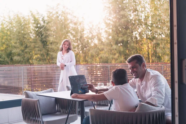 Ein glückliches älteres Paar, das sich auf dem Balkon eines Luxushauses ausruht, Vater und Sohn mit einem Tablet. Selektiver Fokus — Stockfoto