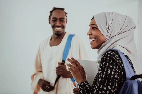 幸せなアフリカの学生のグループは、会話やチームの会議で一緒に仕事をしている伝統的なスダンイスラム教徒のヒジャーブファッションを身に着けている宿題の女の子 — ストック写真