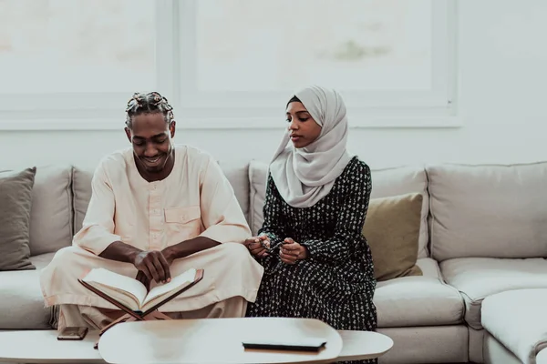 Afrikanska muslimska par hemma i ramadan läser Koranen järnek islam bok. — Stockfoto