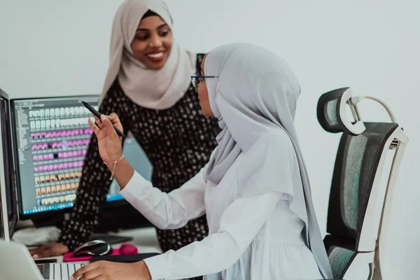 Ofisteki iki genç Afro Amerikalı modern Müslüman iş kadını yaratıcı, parlak ofis işyerinde büyük ekranlı eşarp takıyorlar. — Stok fotoğraf